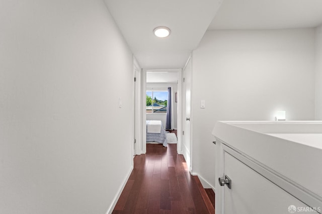 corridor with baseboards and dark wood-type flooring