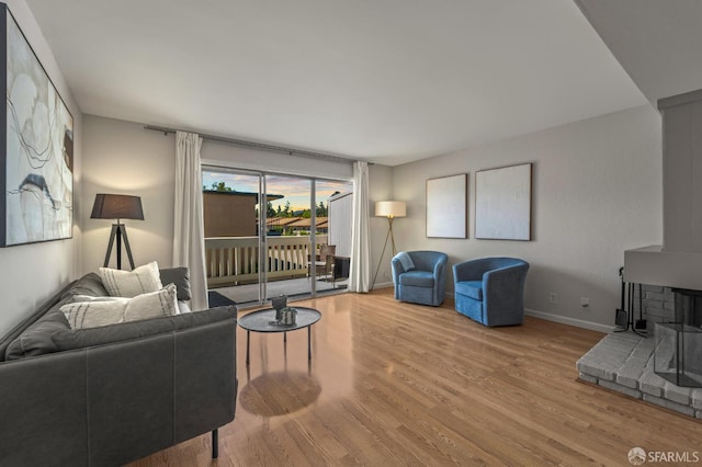 living area featuring a wood stove, wood finished floors, and baseboards