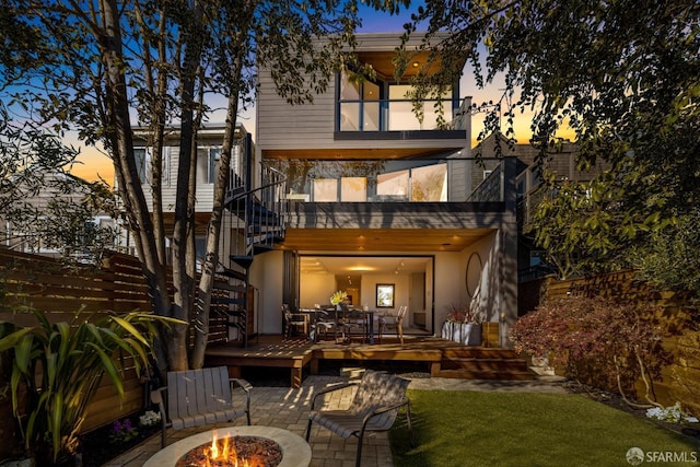 back house at dusk with a balcony and a fire pit