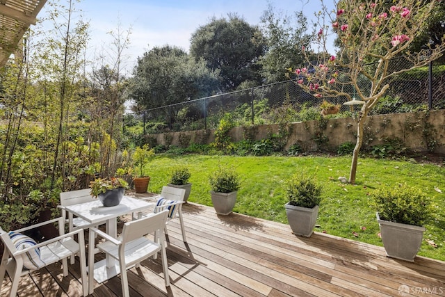 wooden terrace featuring a yard, outdoor dining space, and fence