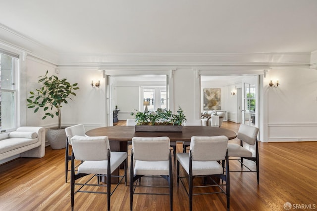 dining space with crown molding and light wood-style floors