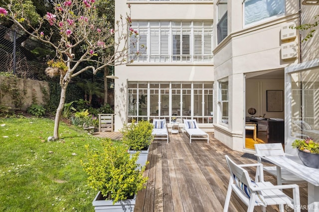 back of house featuring a lawn, a deck, and stucco siding