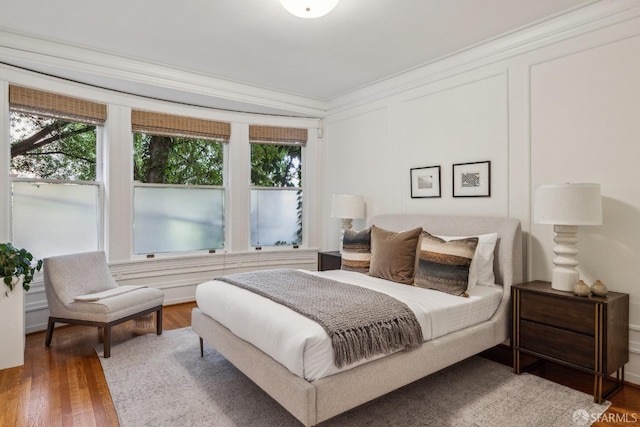 bedroom with multiple windows, wood finished floors, and crown molding