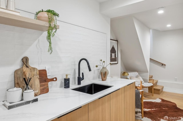 kitchen featuring tasteful backsplash, sink, light stone counters, and light wood-type flooring