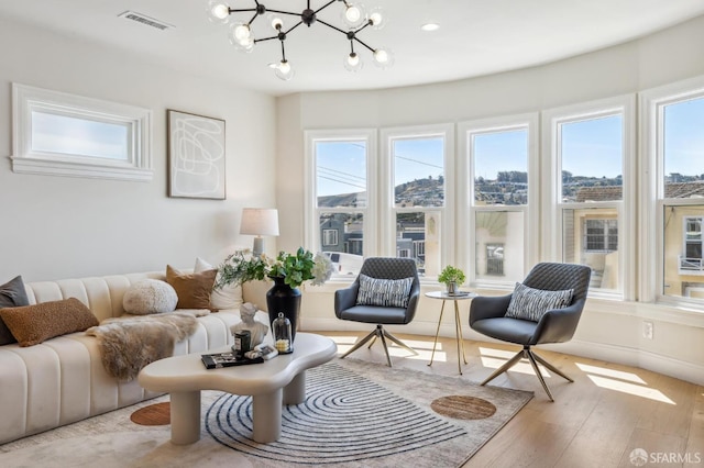 living room with a notable chandelier, light hardwood / wood-style floors, and a healthy amount of sunlight