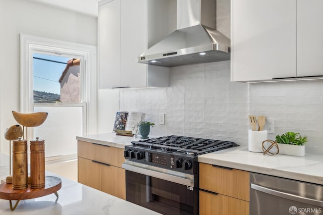 kitchen with range with gas cooktop, light stone counters, dishwasher, wall chimney range hood, and white cabinets