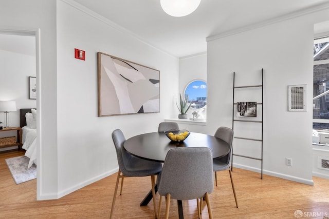 dining room featuring light wood-type flooring and crown molding