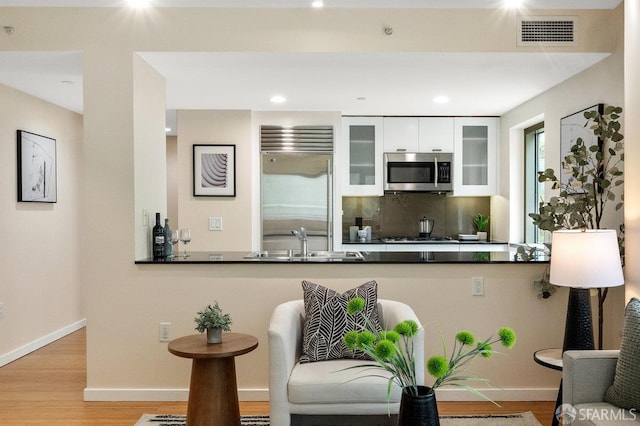 333 1st St Unit N307, San Francisco, CA 94105 - kitchen featuring appliances with stainless steel finishes, a peninsula, wood finished floors, dark countertops, and white cabinetry