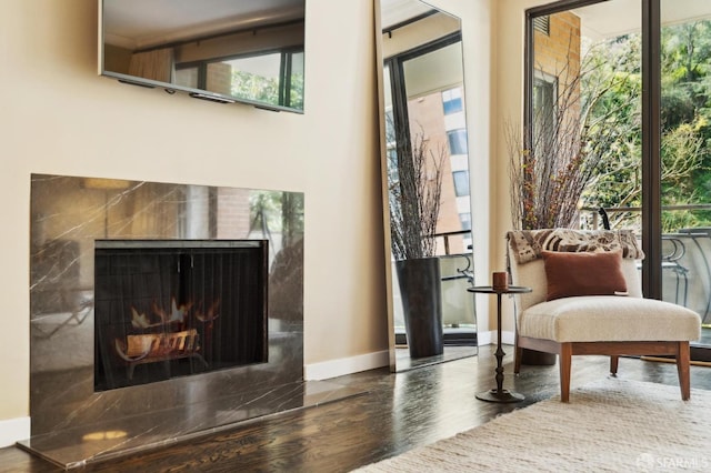 sitting room with a high end fireplace, baseboards, and wood finished floors