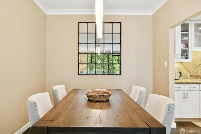 dining room with dark wood-style flooring, crown molding, and baseboards