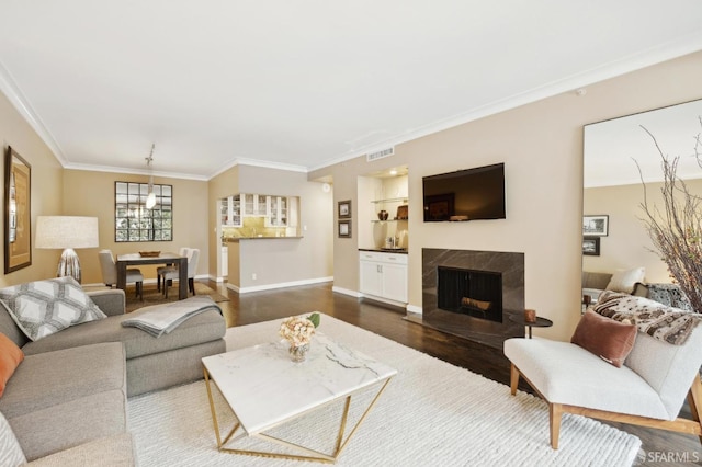 living area with baseboards, visible vents, a tiled fireplace, dark wood-type flooring, and crown molding