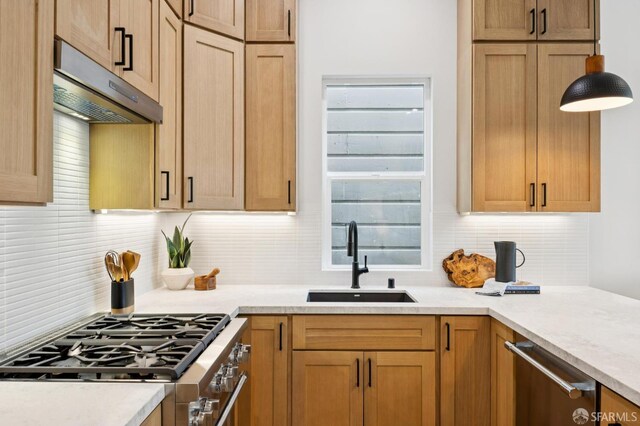 102 Baker St Unit B, San Francisco, CA 94117 - kitchen featuring under cabinet range hood, stainless steel appliances, tasteful backsplash, light countertops, and hanging light fixtures