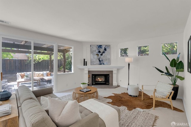 living area featuring baseboards, visible vents, a healthy amount of sunlight, and a brick fireplace