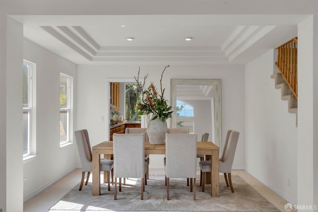 dining room with stairway and a tray ceiling