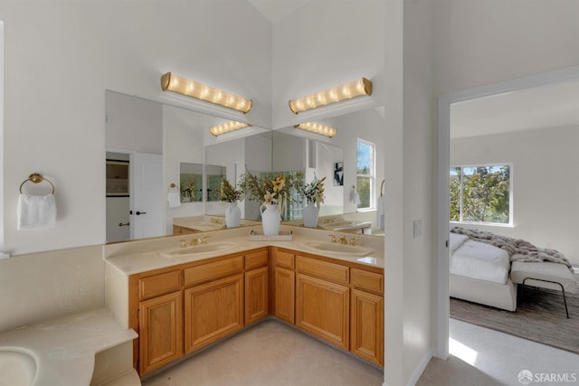 ensuite bathroom featuring double vanity, a high ceiling, ensuite bath, and a sink