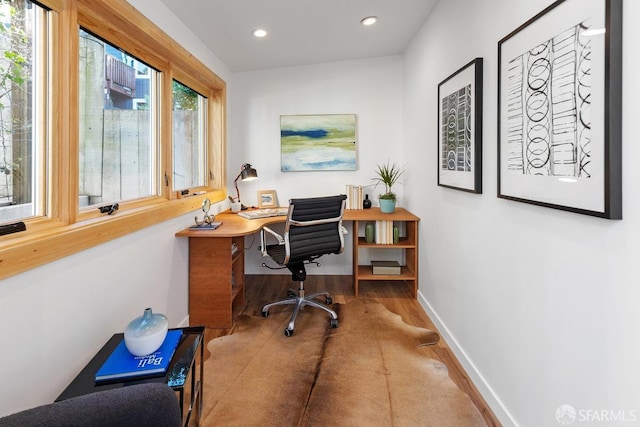 office with hardwood / wood-style floors and a healthy amount of sunlight