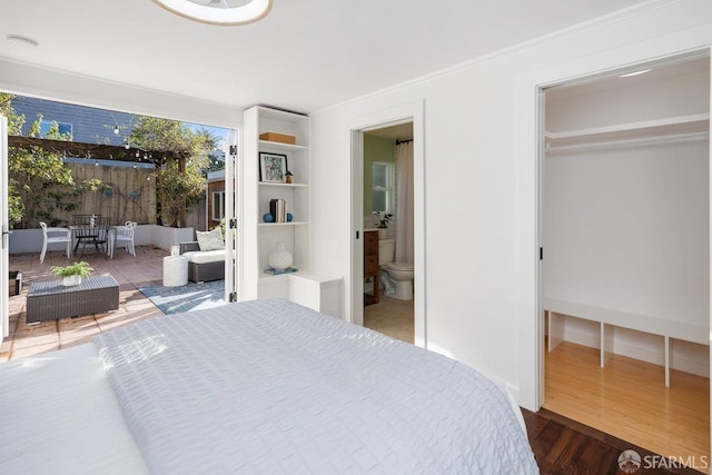 bedroom with a walk in closet, hardwood / wood-style flooring, and ensuite bath