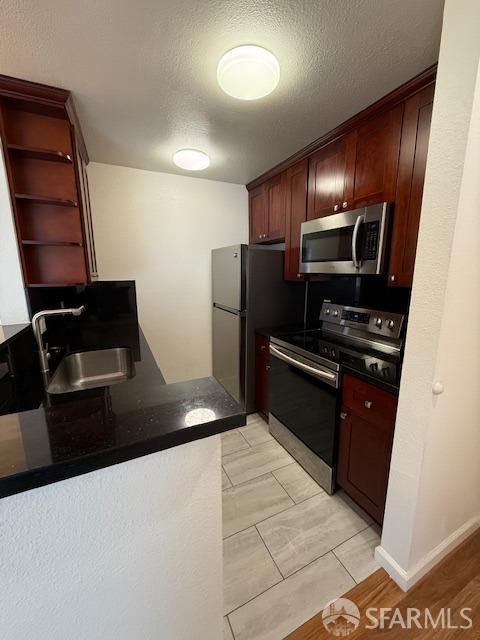 397 Imperial Way Unit 306, Daly City, CA 94015 - kitchen featuring open shelves, dark countertops, a textured ceiling, a sink, and appliances with stainless steel finishes