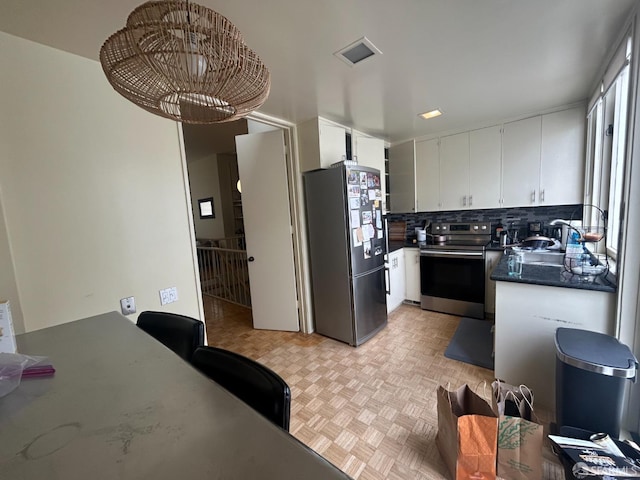 kitchen featuring a sink, white cabinets, dark countertops, and stainless steel appliances