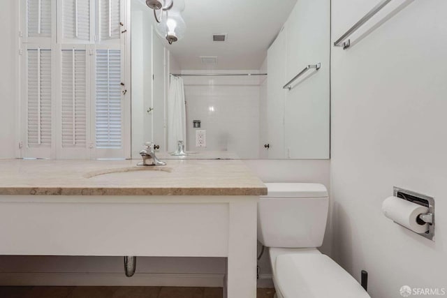 bathroom featuring toilet, a shower with curtain, visible vents, and vanity