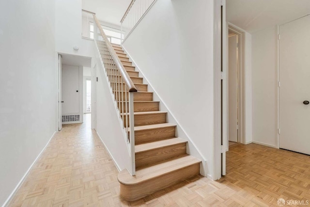 staircase featuring baseboards and a high ceiling