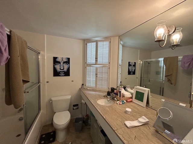 bathroom with toilet, a chandelier, combined bath / shower with glass door, and vanity