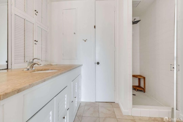 full bath with vanity, tile patterned flooring, visible vents, and tiled shower