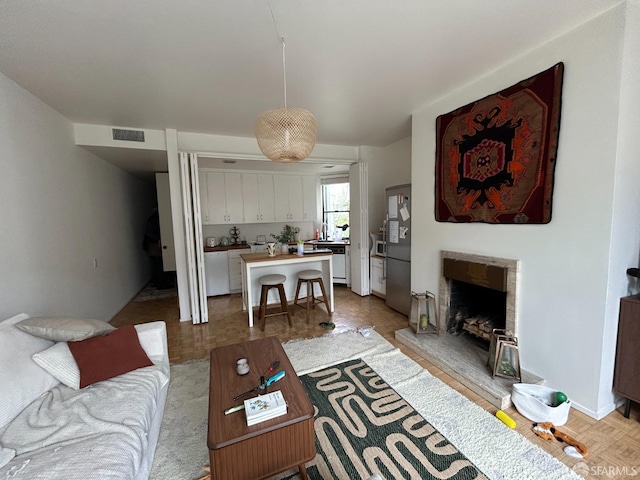 living room with a fireplace with raised hearth and visible vents