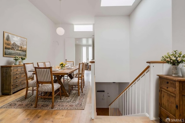 dining space with a skylight, wood finished floors, and a towering ceiling