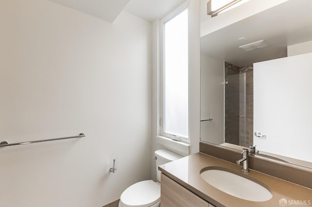 bathroom with vanity, toilet, and tiled shower