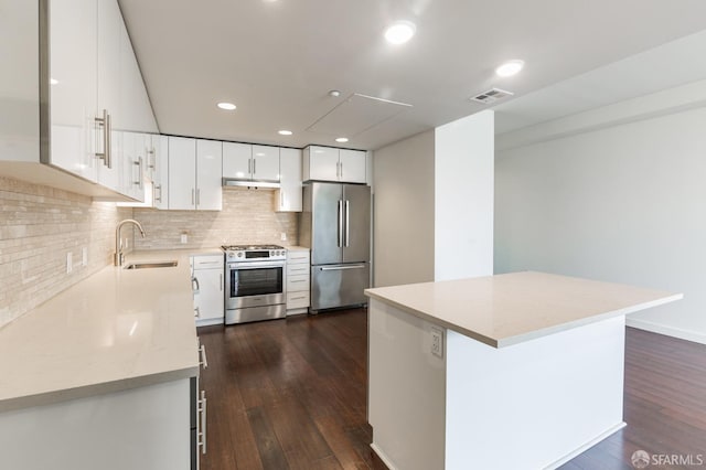 kitchen with dark wood-style flooring, stainless steel appliances, visible vents, a sink, and under cabinet range hood