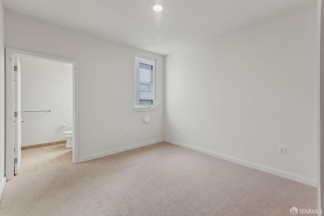 unfurnished room with light carpet and baseboards