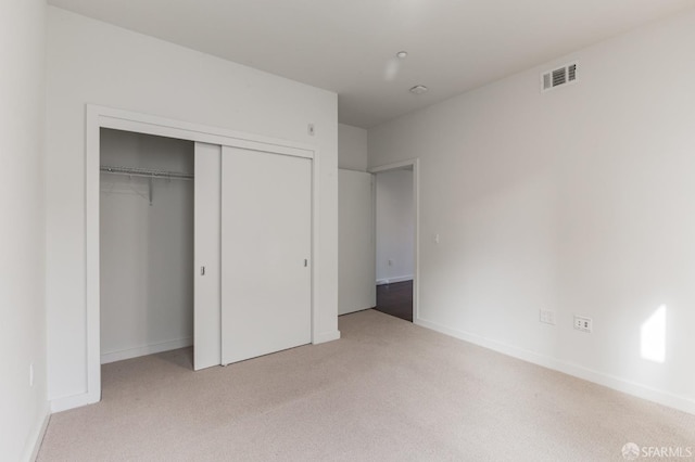 unfurnished bedroom featuring light colored carpet and a closet