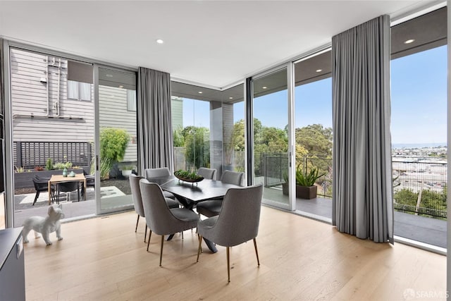 dining area with light hardwood / wood-style floors and a wall of windows