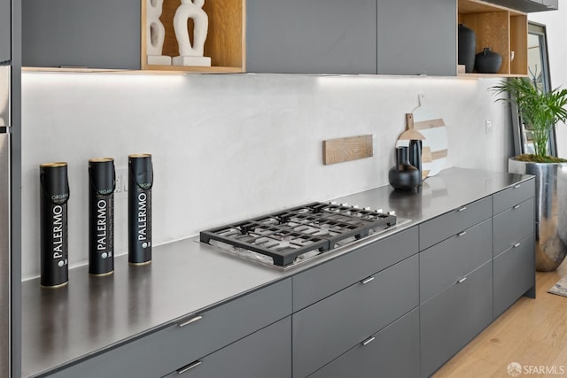 kitchen with gray cabinetry, light wood-type flooring, and stainless steel gas stovetop