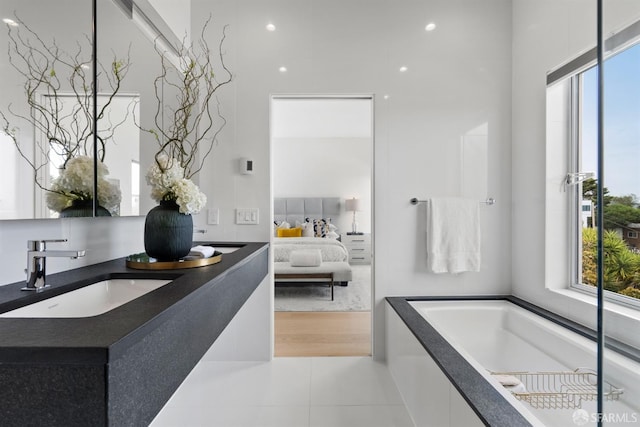 bathroom with tile patterned flooring, vanity, and a relaxing tiled tub