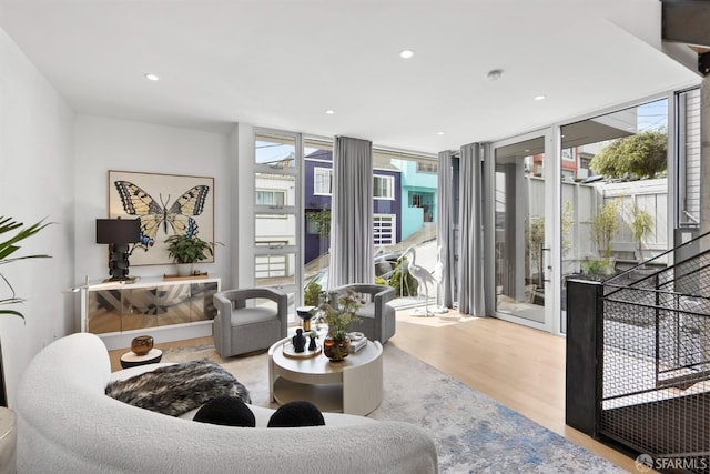 living room with a wealth of natural light, light hardwood / wood-style flooring, and a wall of windows