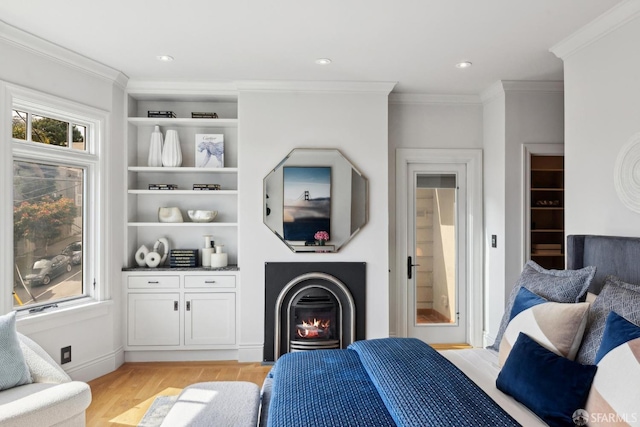 bedroom featuring ornamental molding, light wood-type flooring, a glass covered fireplace, and recessed lighting