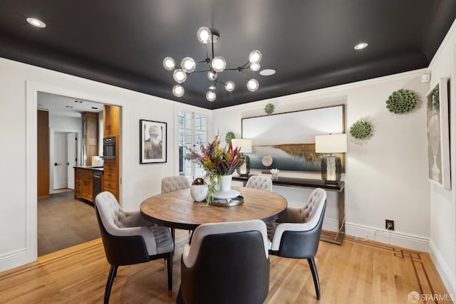 dining area with light wood-type flooring, a notable chandelier, and baseboards