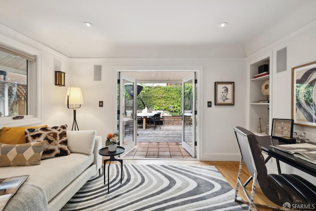 living room with light wood-style flooring, recessed lighting, baseboards, built in features, and ornamental molding