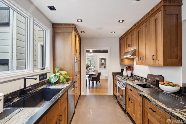 kitchen with stainless steel appliances, brown cabinets, a sink, and under cabinet range hood