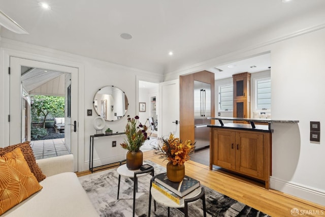 living area featuring baseboards, ornamental molding, and light wood-style floors