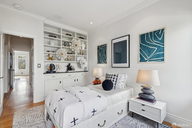 bedroom featuring ornamental molding, light wood-style flooring, and baseboards