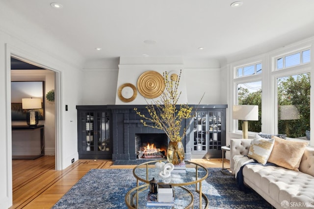 living room featuring recessed lighting, a fireplace, baseboards, and wood finished floors