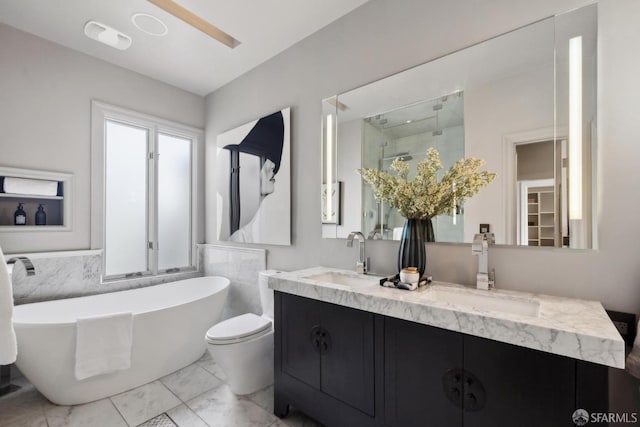 full bathroom featuring double vanity, marble finish floor, a freestanding bath, and a sink