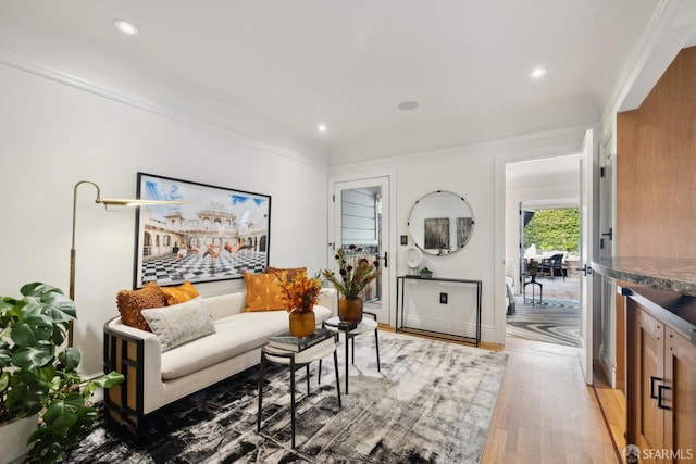 living area featuring light wood-style floors, baseboards, crown molding, and recessed lighting