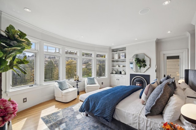 bedroom with baseboards, a glass covered fireplace, ornamental molding, light wood-type flooring, and recessed lighting