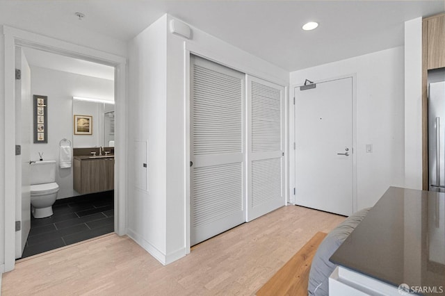 hallway featuring a sink, wood finished floors, and recessed lighting