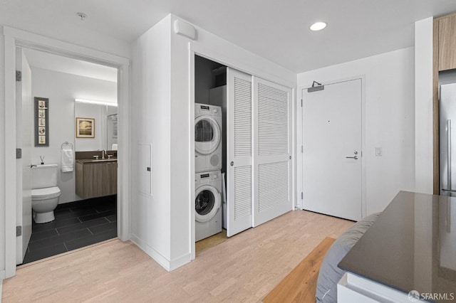 laundry room featuring stacked washer and dryer, light wood-type flooring, laundry area, and a sink