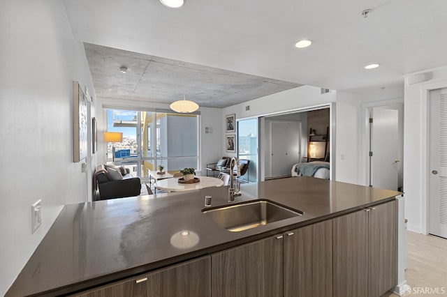 kitchen with dark countertops, a sink, dark brown cabinetry, and modern cabinets